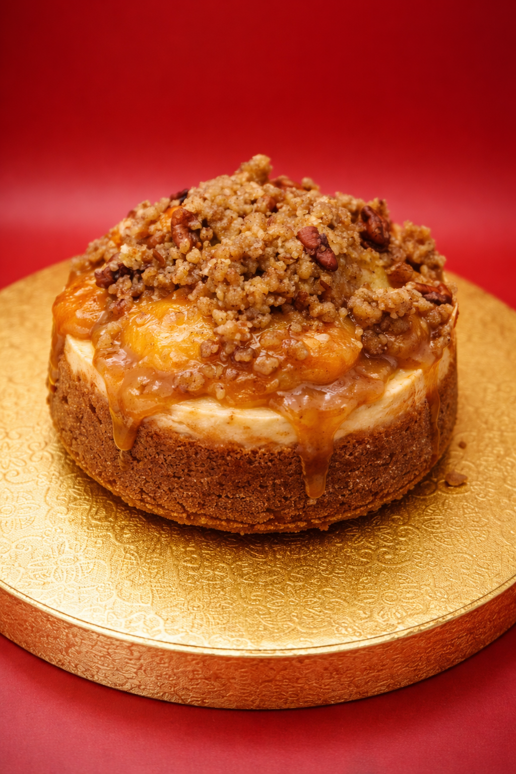 Cheesecake with crumb topping on a gold plate against a red background