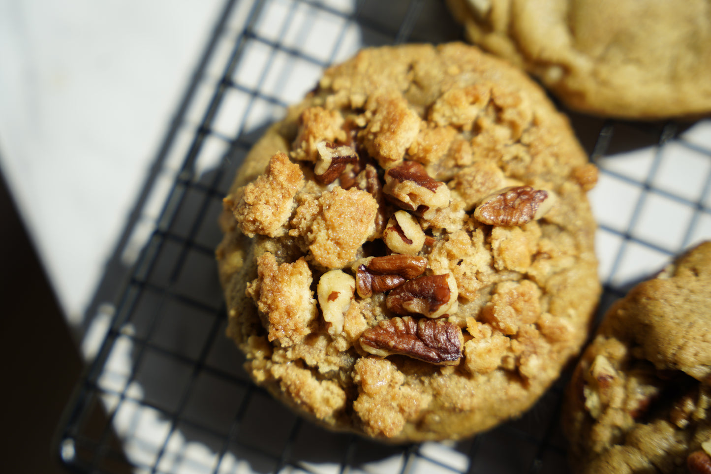Cookie with crumbly topping and pecans on a cooling rack