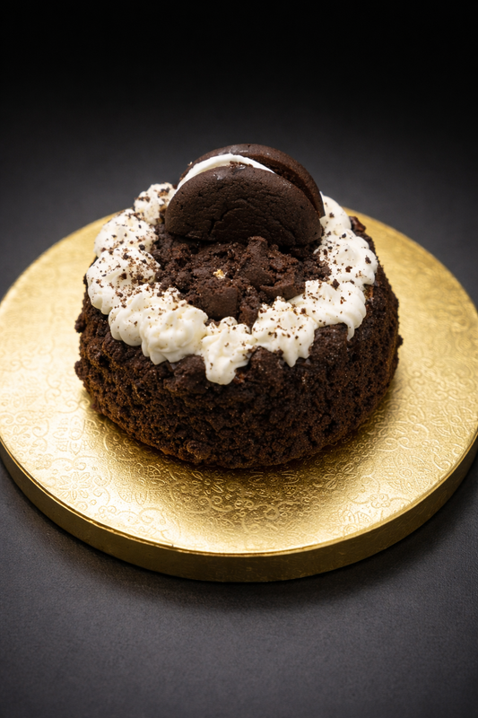 Chocolate cake with white cream and a cookie on a gold plate against a dark background