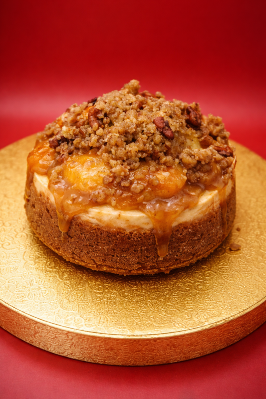 Cheesecake with crumb topping on a gold plate against a red background